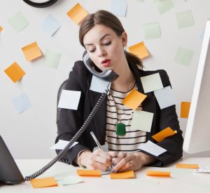 Studio shot of young woman working in office covered with adhesive notes